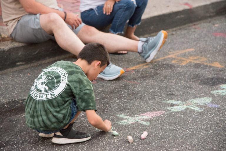 A child drawing with chalk at Downtown Sounds